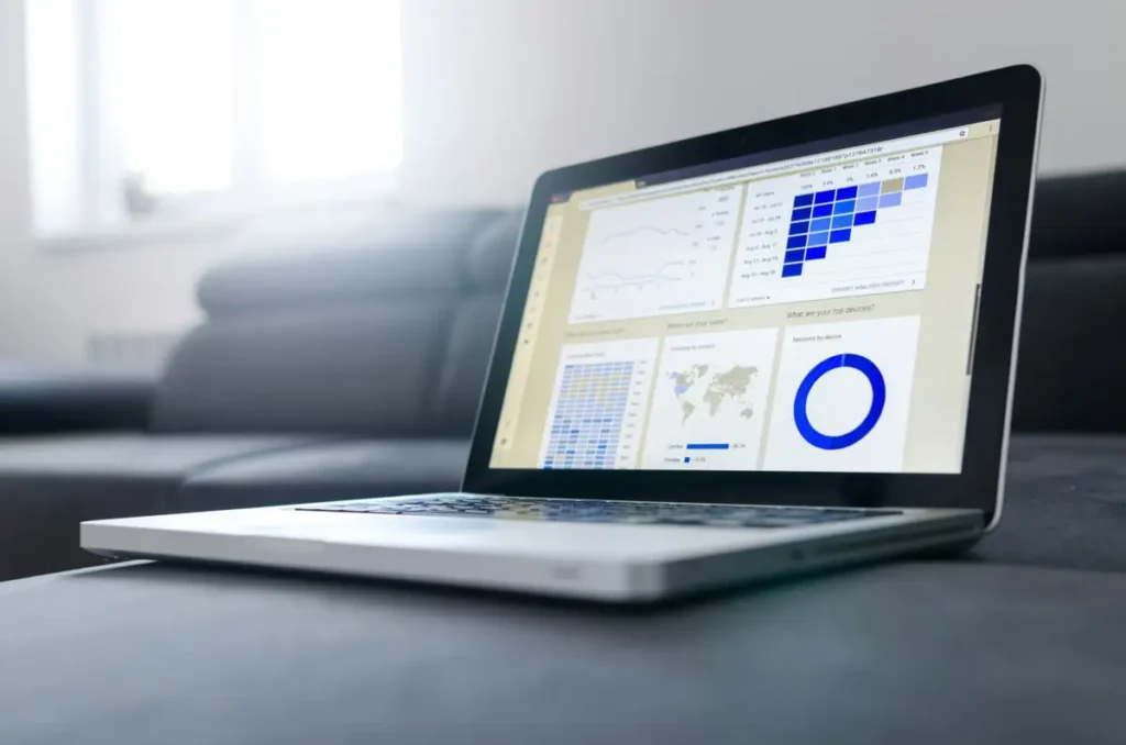 ノートパソコンの画面に表示された Google Analytics 風のコホート分析ダッシュボード、青いグラフとヒートマップ